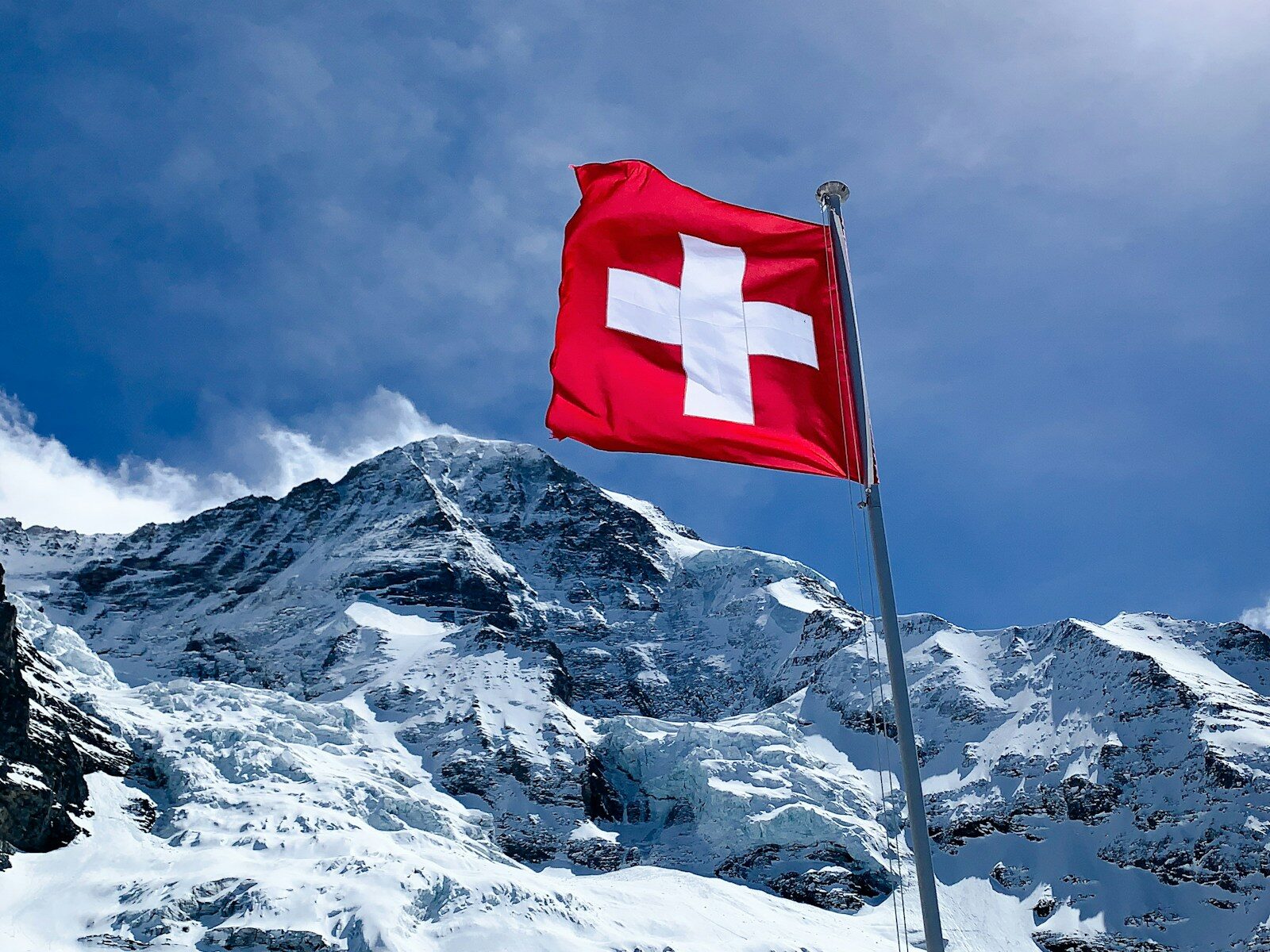 Drapeau suisse au sommet enneigé illustrant la demande de retraite suisse depuis la France